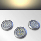 Three circular warm white LED kitchen cabinet lights with silver rims on a white background