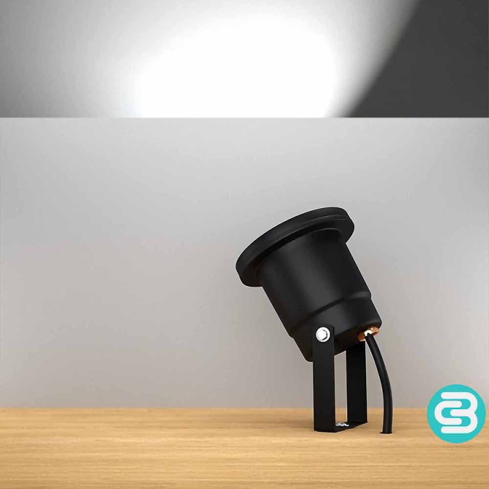 Black outdoor light fixture on a wooden surface with a white LED light on a gray background.