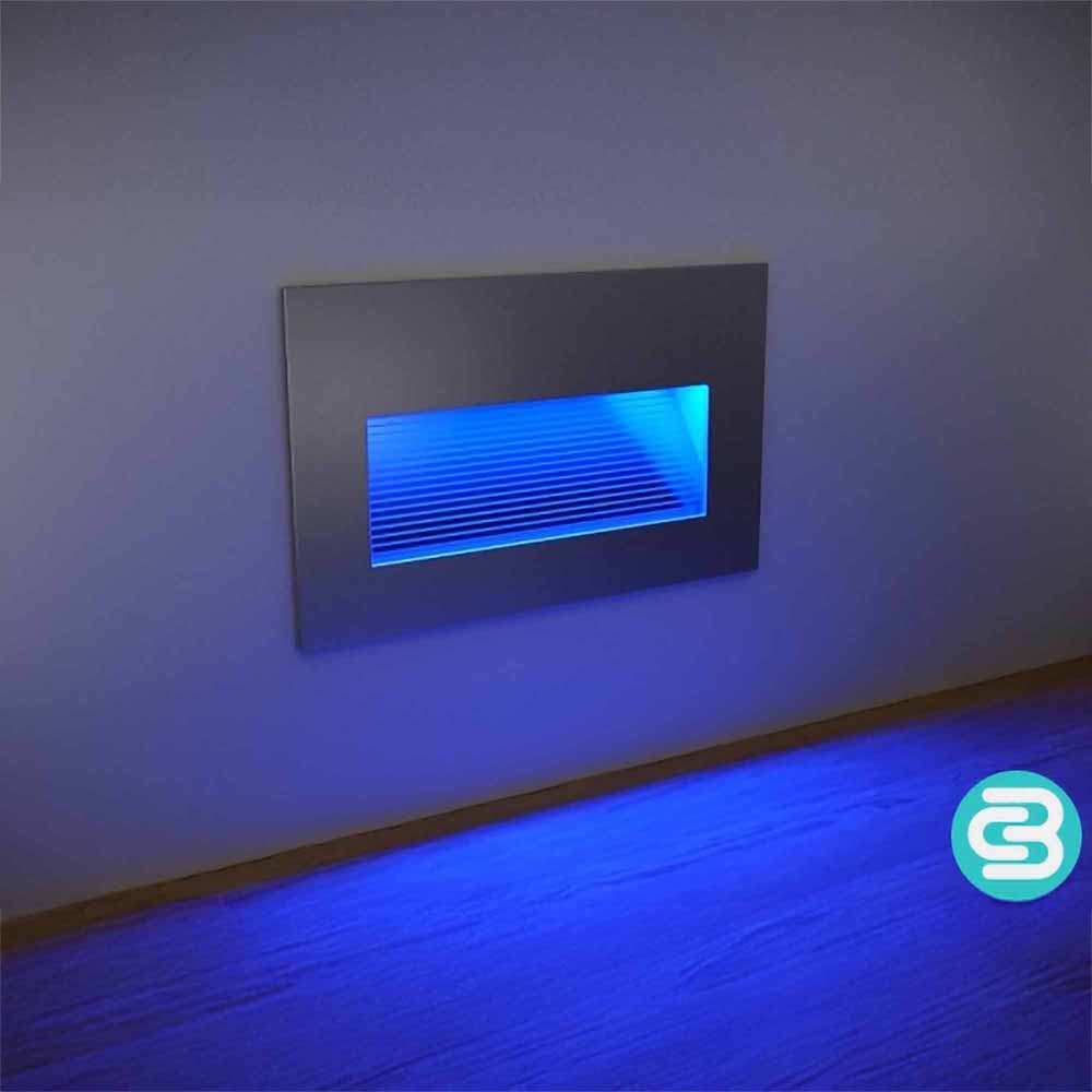 Modern wall-mounted light fixture emitting a blue glow on a gray wall.