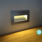Modern wall-mounted light fixture emitting a warm white glow on a gray wall.